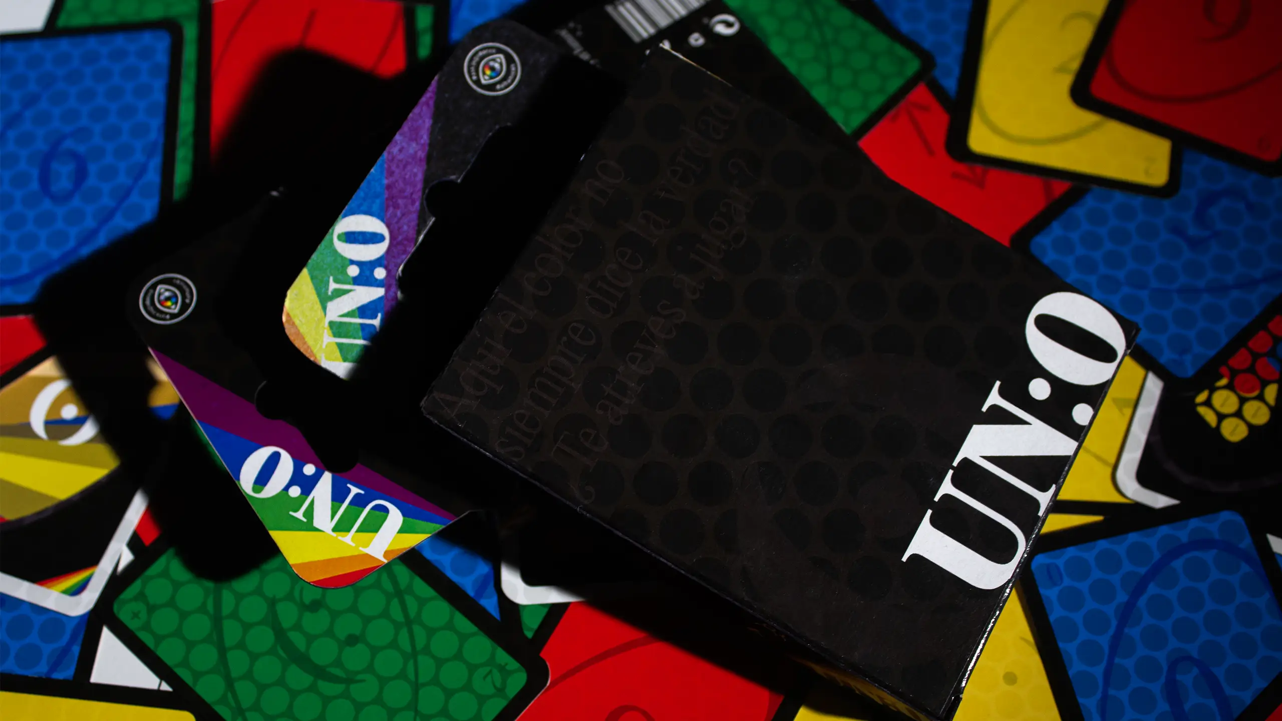 Packaging de la baraja de NOCROM rodeado de las cartas de la baraja UNO